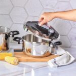 یک عکس زیبا از زودپز دو قلو 4 و 6 لیتری کاراجا Perfect قرمز2483 که شخصی در آن را باز میکند.